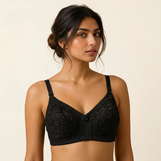 A woman modeling a black lace underwire bra with adjustable shoulder straps against a plain beige studio background.