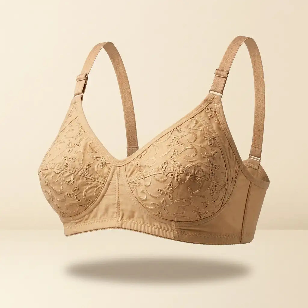 A beige underwire bra with intricate floral lace embroidery on the cups and adjustable shoulder straps, shown floating against a solid cream background.