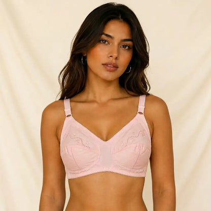 A woman modeling a light pink seamless bralette with scalloped lace detailing on the cups, set against a soft beige fabric backdrop.