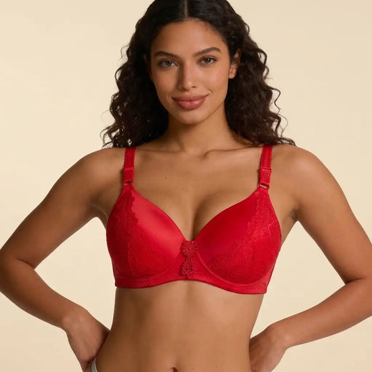 A woman modeling a bright red lace underwire bra against a solid beige background.